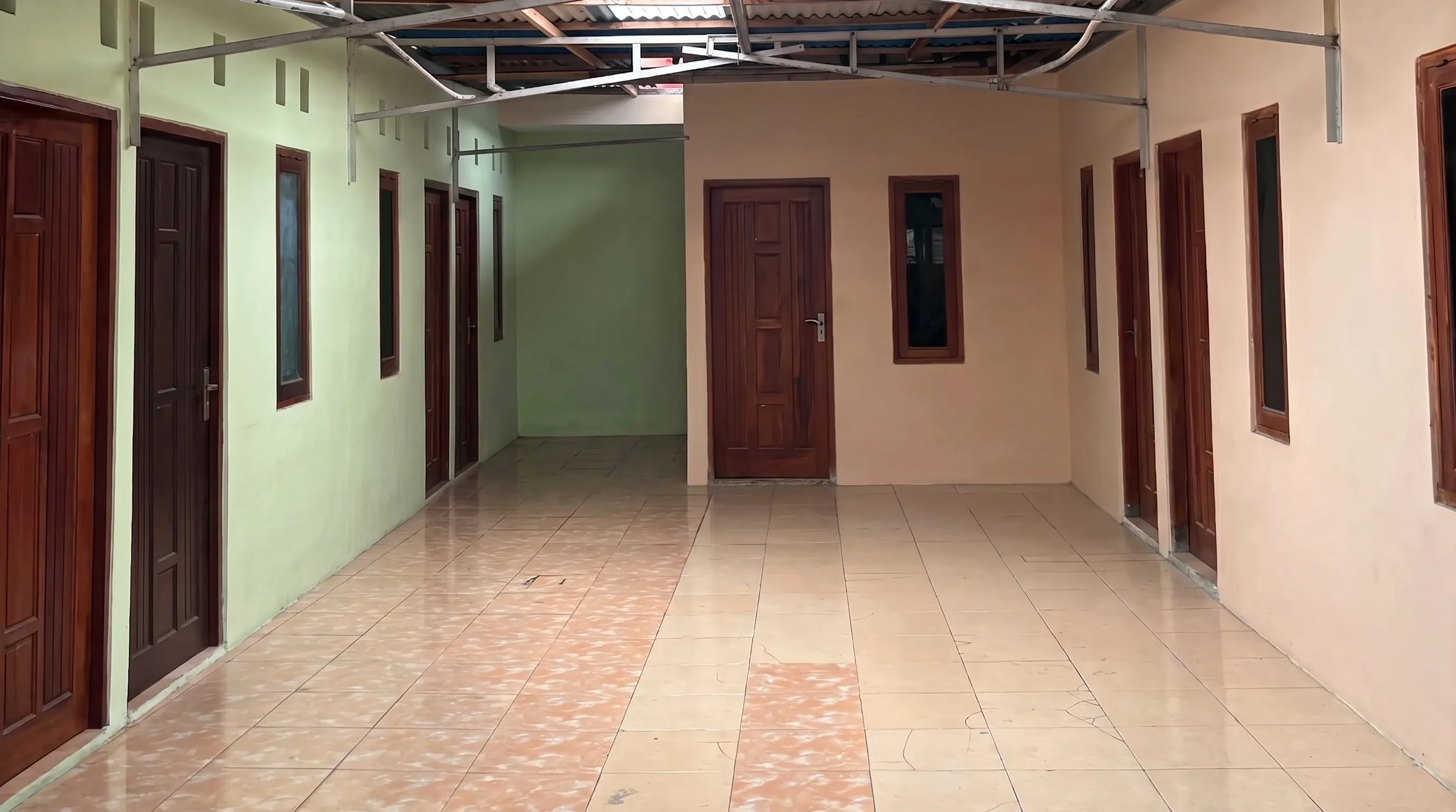 Lorong beratap untuk parkir motor penghuni, diapit pintu-pintu kamar